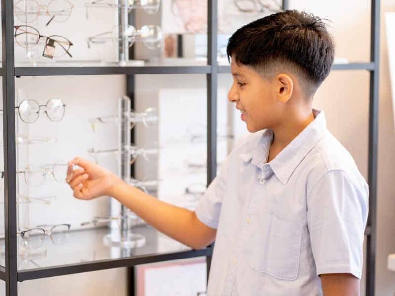 indian-boy-hold-glasses-on-shelf-during-selection-to-buy-some-products-for-his-eyecare.jpg